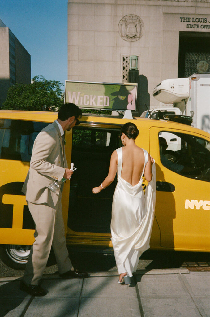 Bride and groom hop into a cab after eloping in New York City.