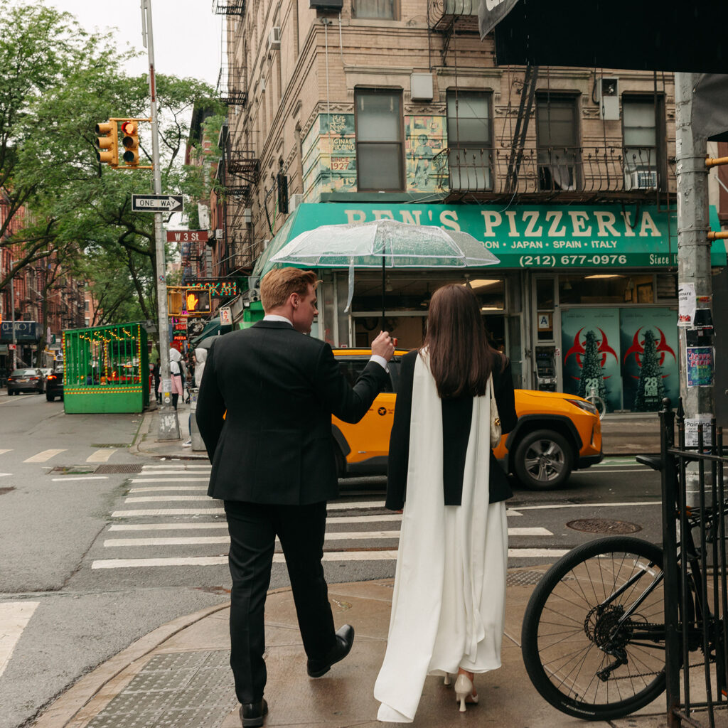After eloping, a couple takes photos on a rainy New York day in front of a pizzeria.