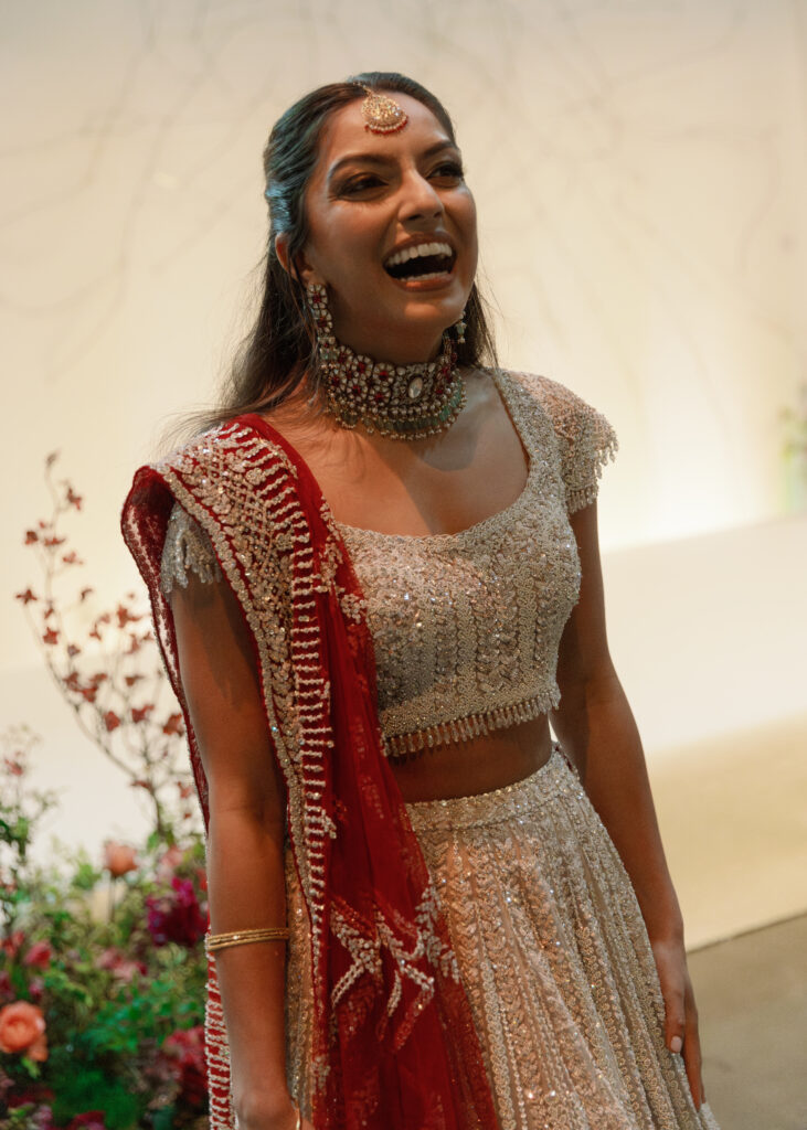 Kismet’s lehenga catches the light with each step, the red dupatta brushing through the florals as the room shifted around her. 